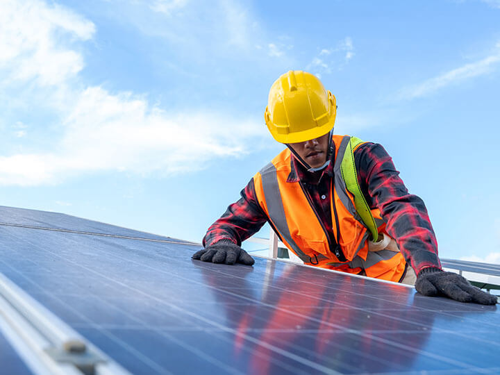 Engineer in safety harness and hard hat doing a functional safety test on a solar panel