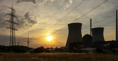 A nuclear power plant featuring cooling towers and power lines against a clear sky.