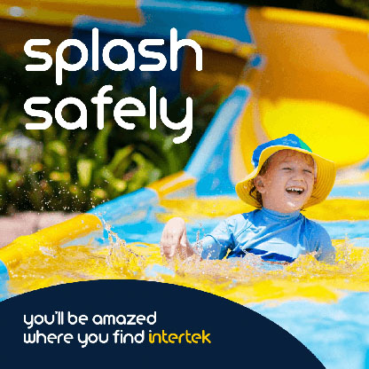 A young boy smiling as he comes down a water slide